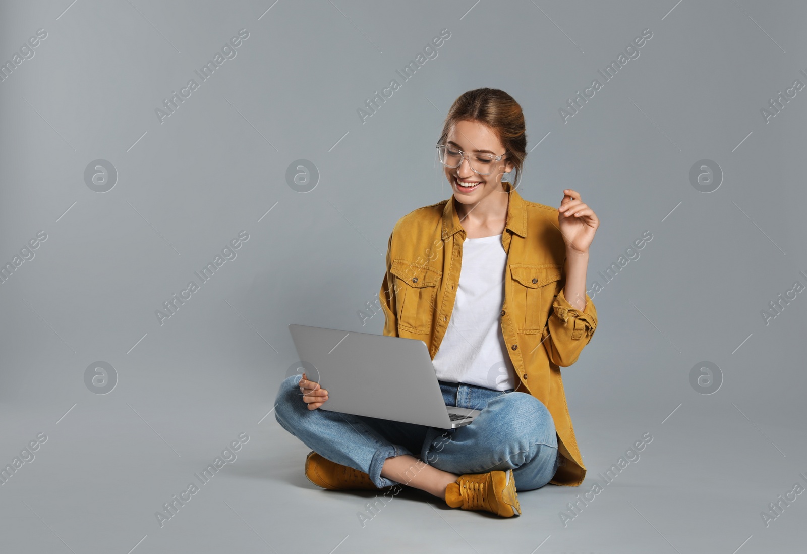 Photo of Young woman with laptop on grey background