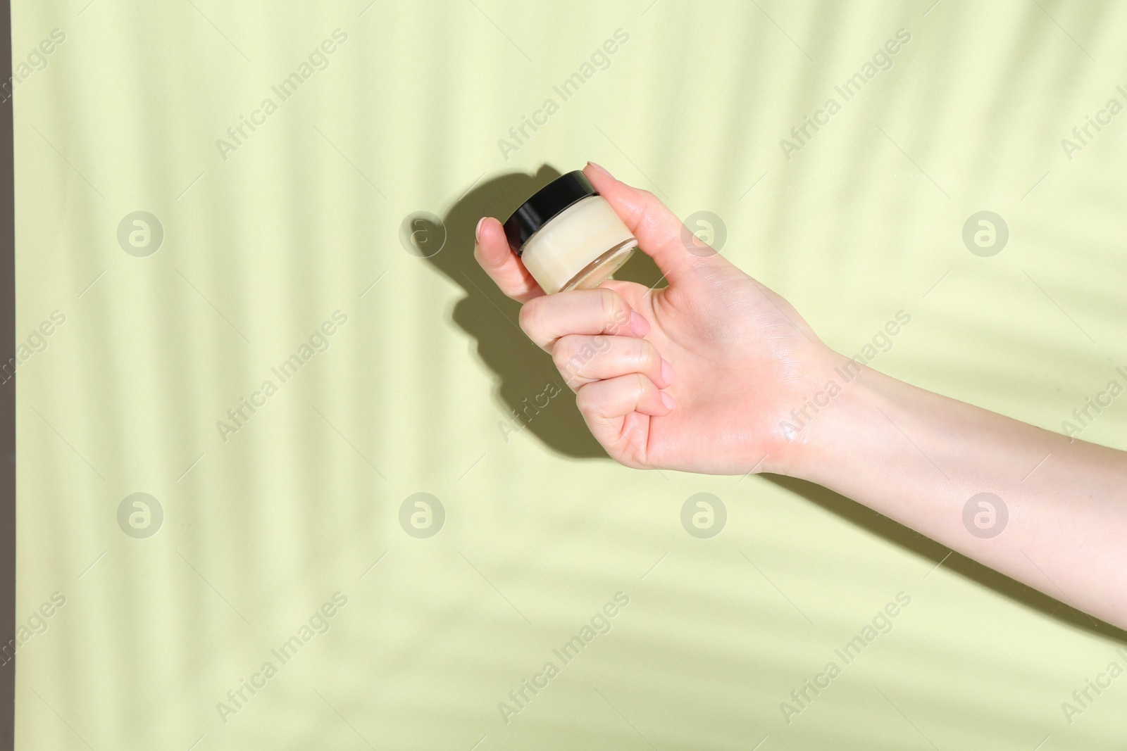 Photo of Woman holding jar of cream on green background, closeup. Space for text