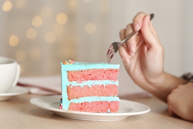 Photo of Woman eating fresh delicious birthday cake at table, closeup