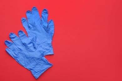 Pair of medical gloves on red background, flat lay. Space for text