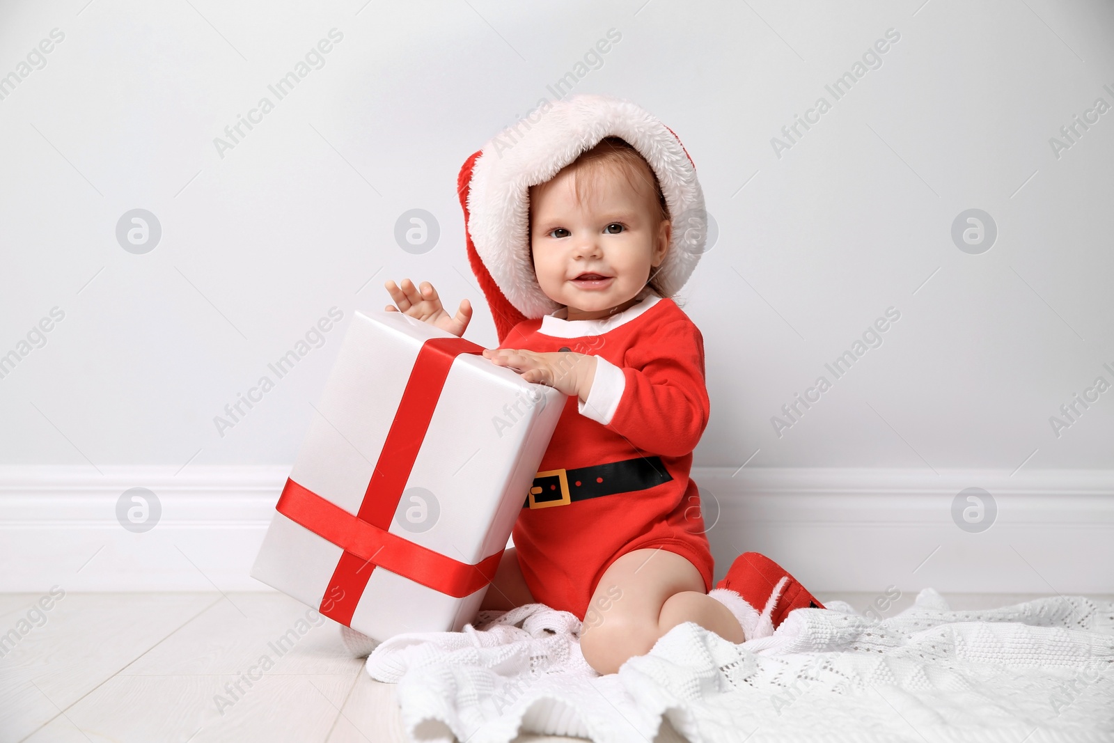 Photo of Cute little baby in Christmas costume with gift at home