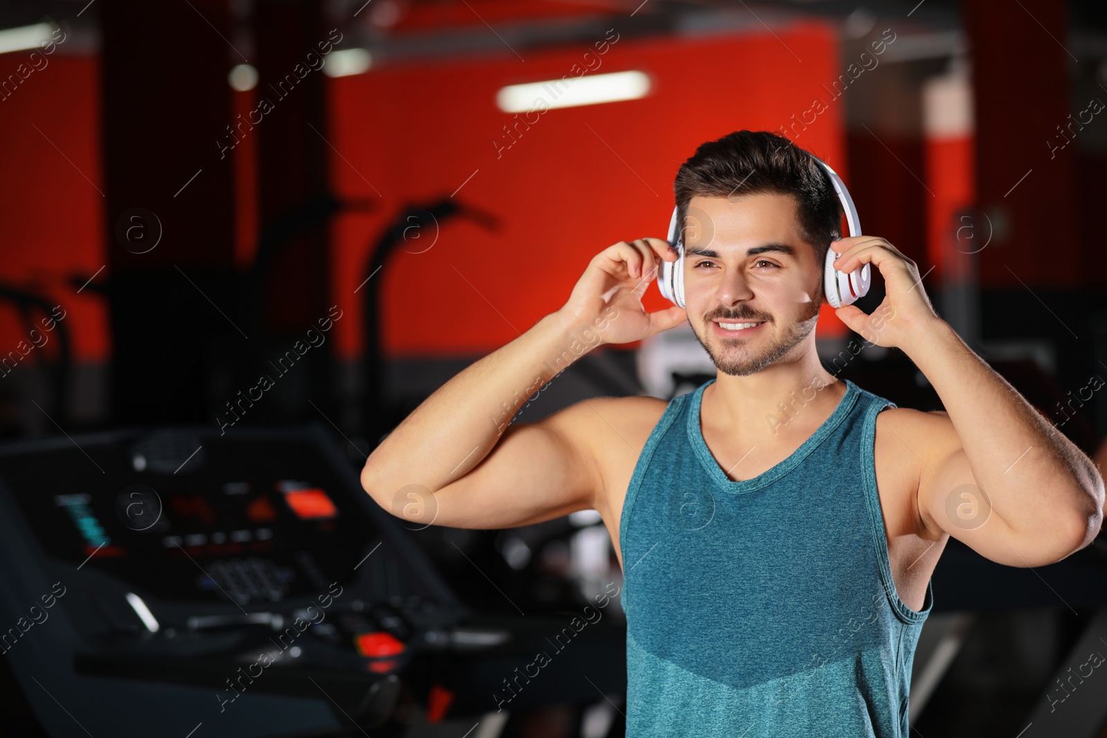 Photo of Young man listening to music with headphones at gym