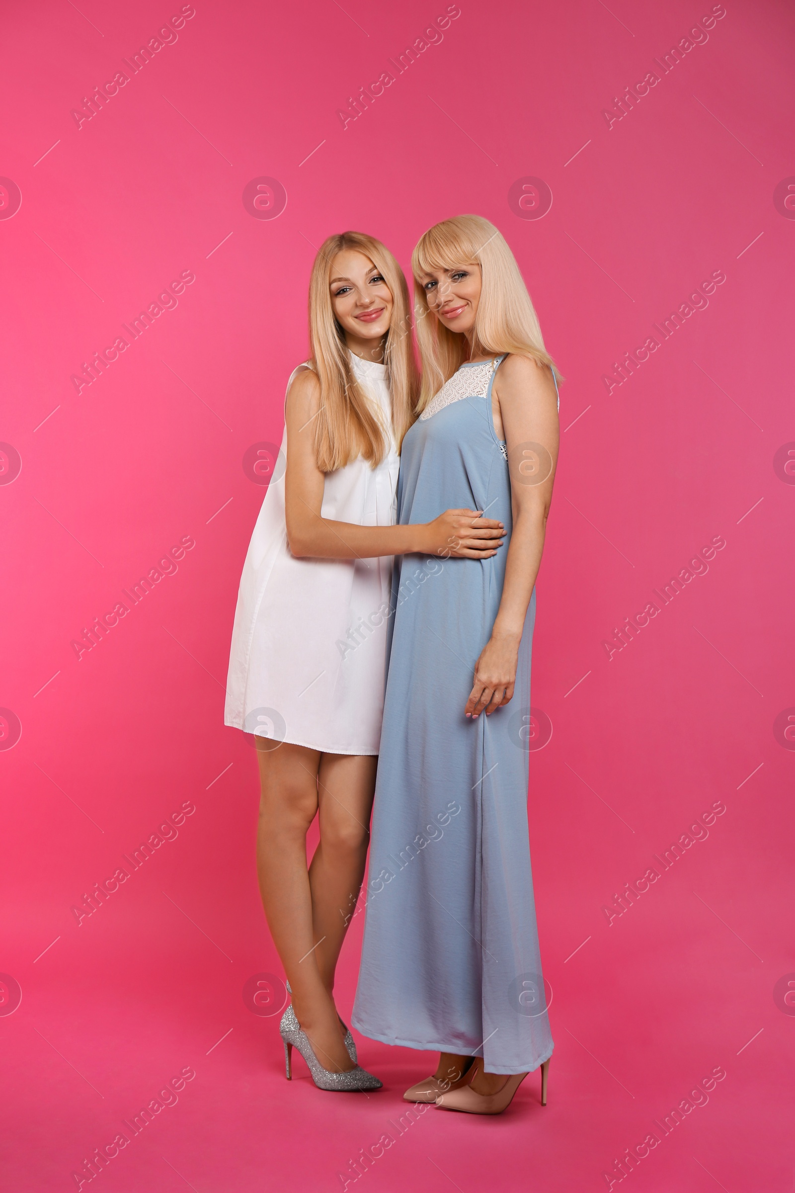 Photo of Portrait of young woman with her mature mother on pink background
