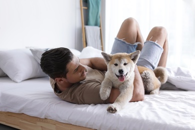 Man and adorable Akita Inu dog in bedroom