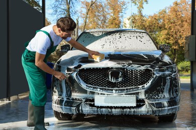 Photo of Worker washing auto with sponge at outdoor car wash