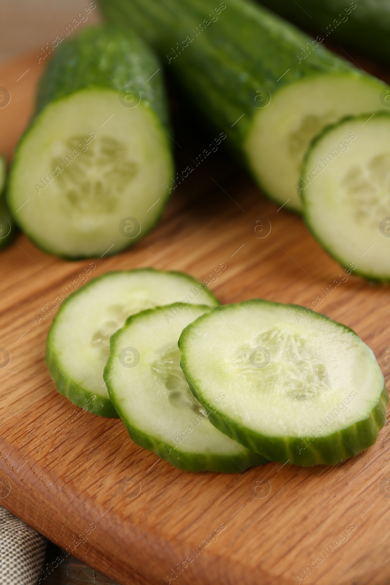 Photo of Fresh cucumbers on wooden cutting board, closeup