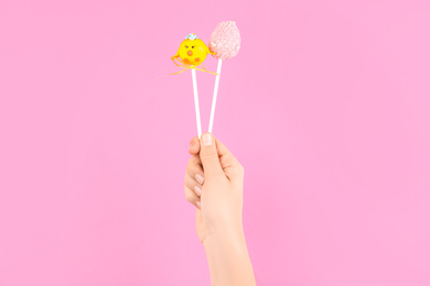 Photo of Woman with delicious cake pops on pink background, closeup. Easter holiday
