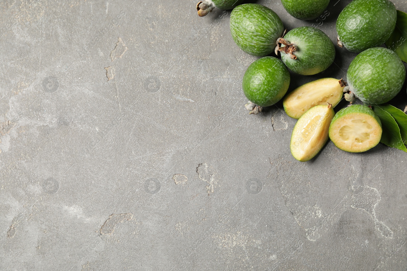 Photo of Fresh green feijoa fruits on grey table, flat lay. Space for text