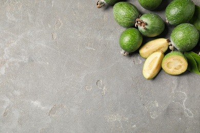 Fresh green feijoa fruits on grey table, flat lay. Space for text