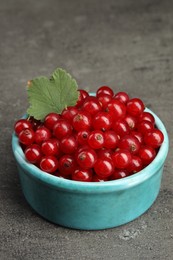 Photo of Ripe red currants in bowl on dark textured table, closeup