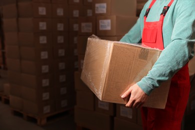 Photo of Worker with cardboard box in warehouse, closeup. Wholesaling