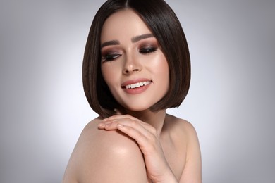 Image of Portrait of pretty young woman with brown hair smiling on grey background