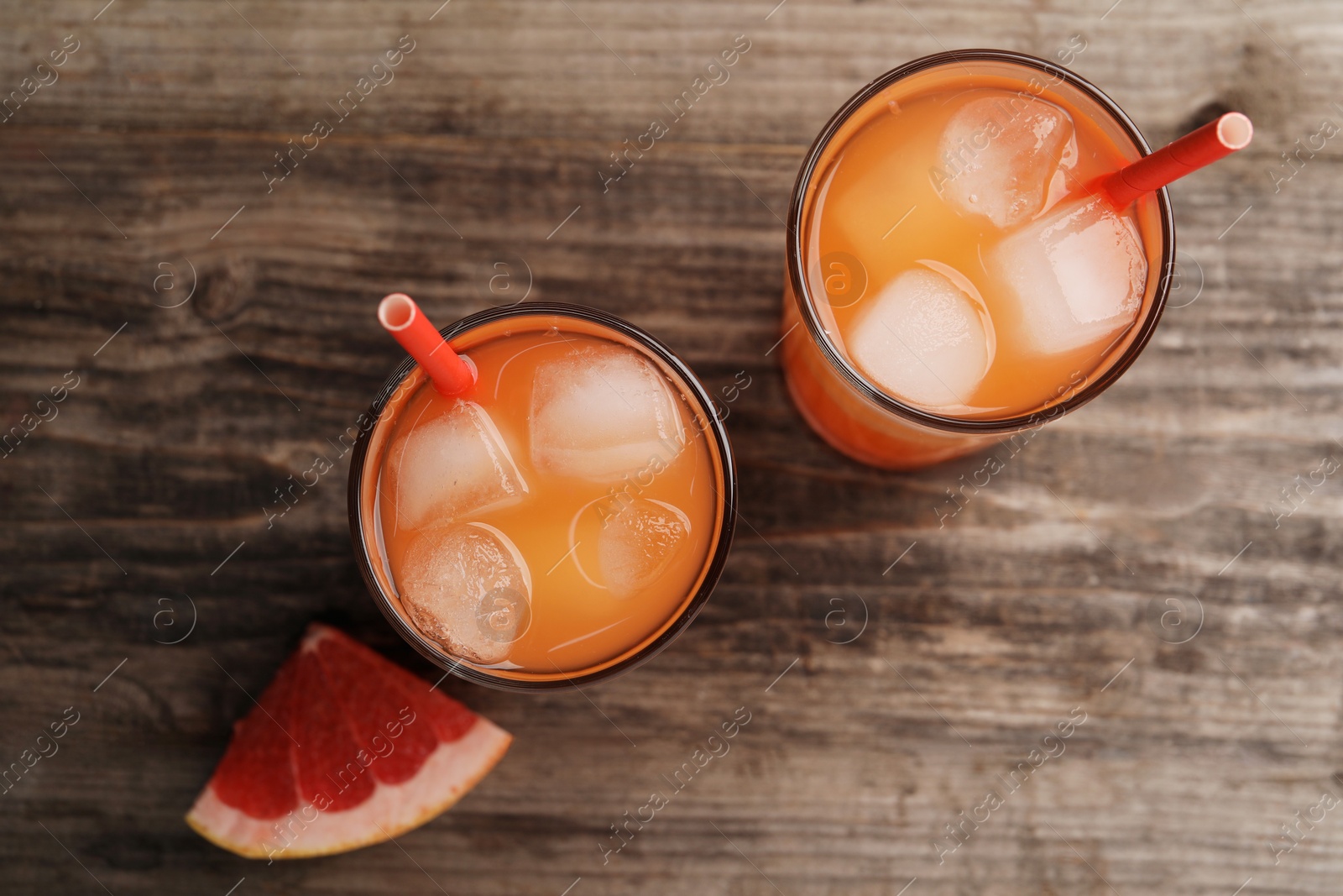 Photo of Tasty freshly made grapefruit juice and fruit on wooden table, top view