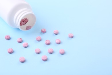 Photo of Jar with vitamin pills on light blue background, space for text