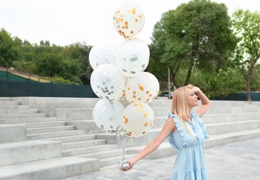 Photo of Beautiful young woman with bunch of balloons outdoors