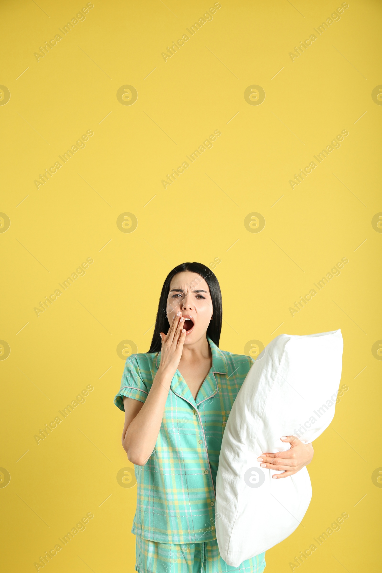 Photo of Young woman with pillow on yellow background