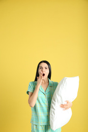 Photo of Young woman with pillow on yellow background