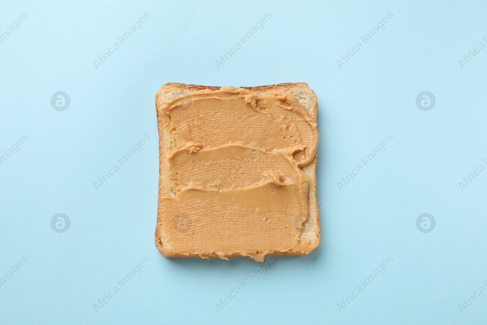 Photo of Tasty peanut butter sandwich on light blue background, top view