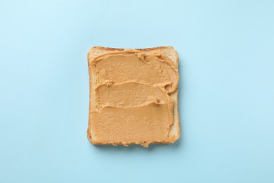 Photo of Tasty peanut butter sandwich on light blue background, top view