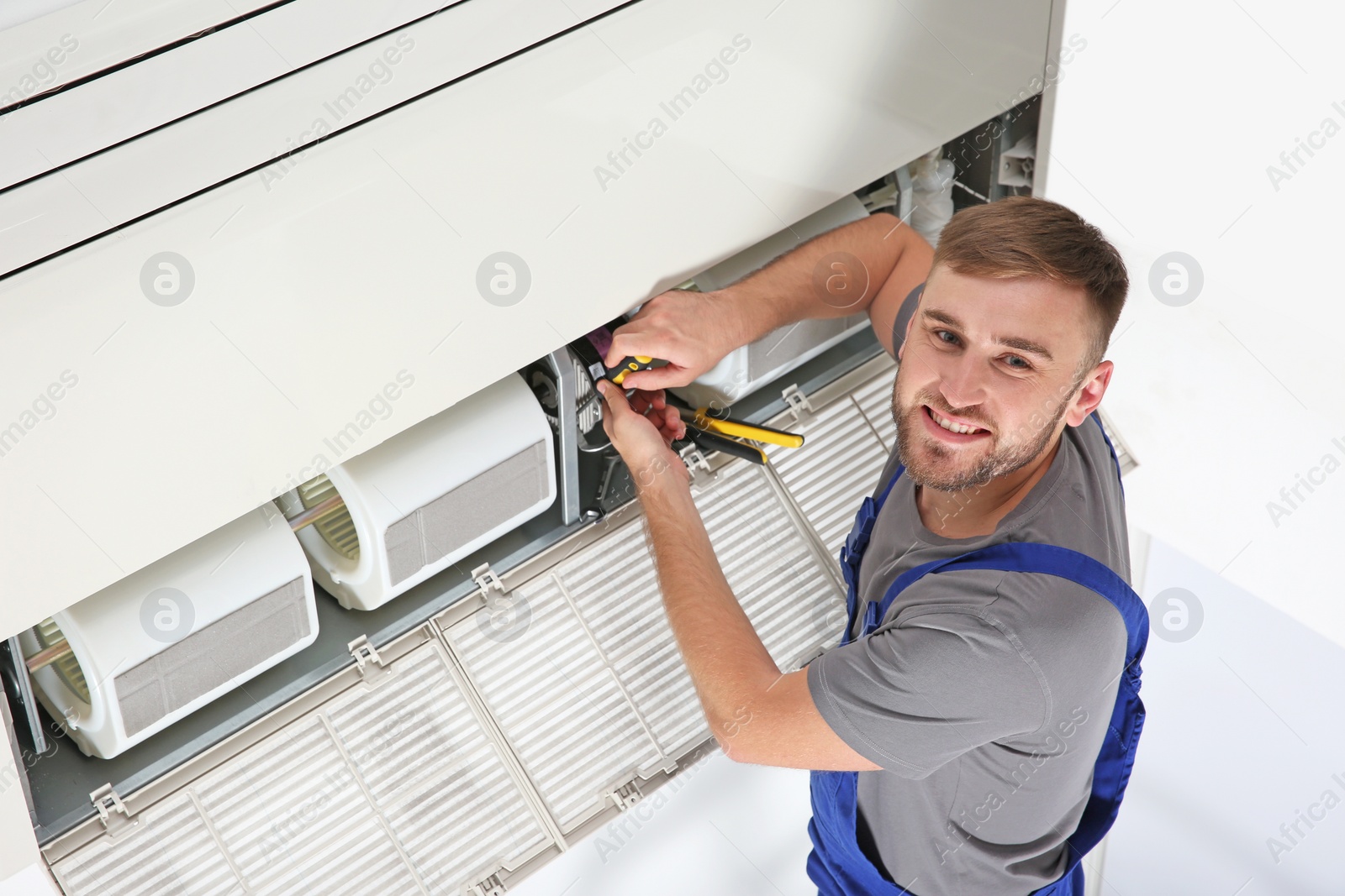 Photo of Young male technician repairing air conditioner indoors