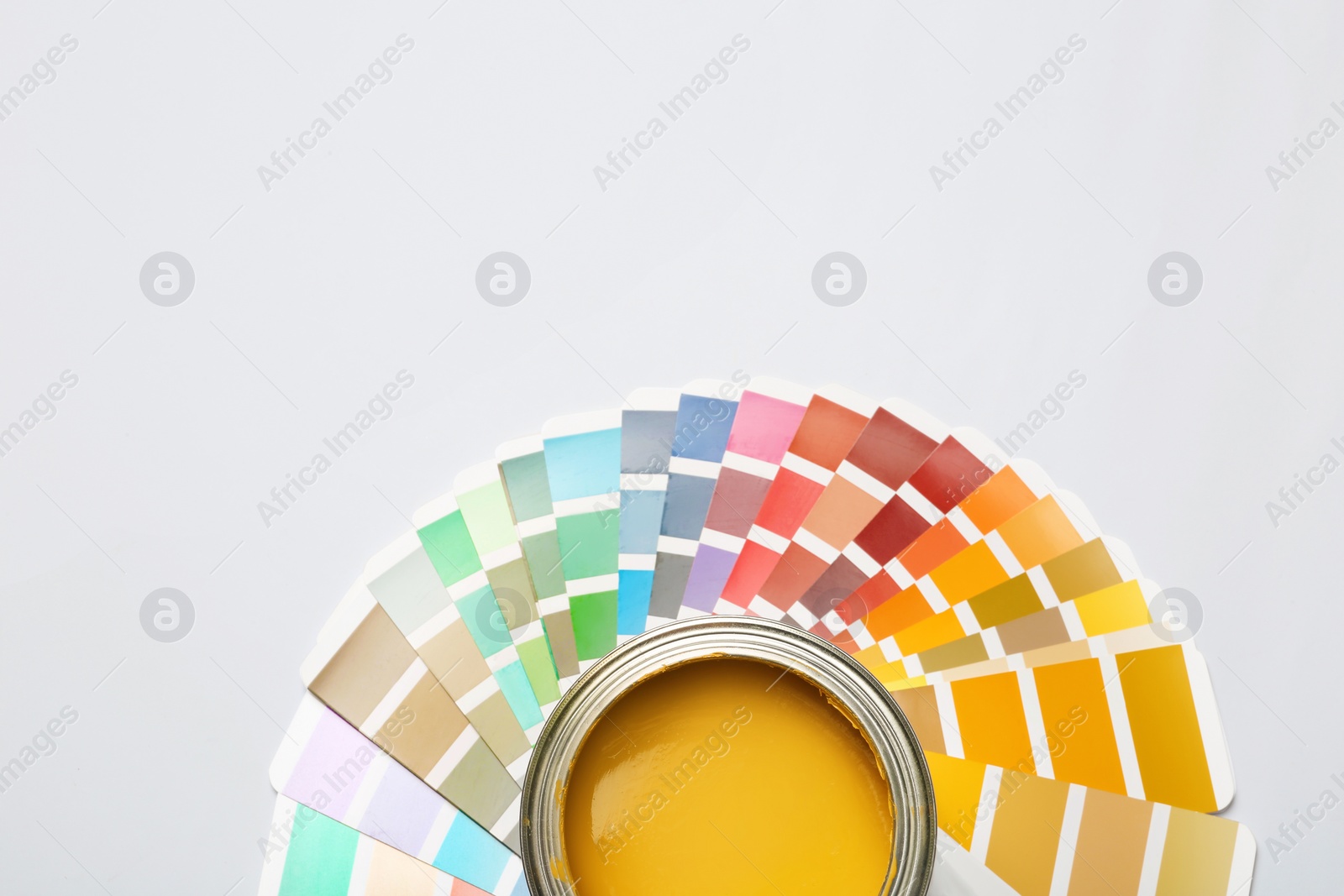 Photo of Yellow paint can and color palette on white background, top view. Space for text