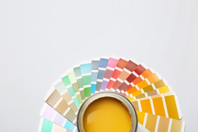 Yellow paint can and color palette on white background, top view. Space for text