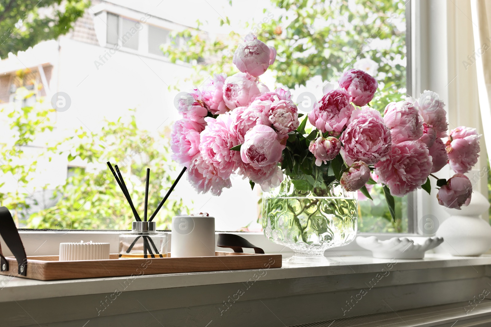 Photo of Beautiful pink peonies in vase on window sill. Interior design