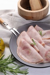 Photo of Tasty ham with rosemary and carving fork on white table