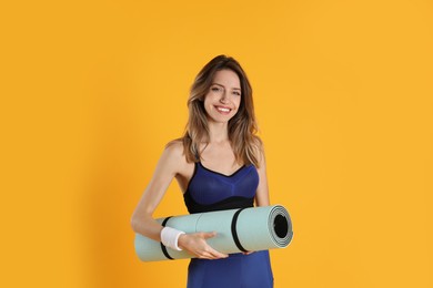 Beautiful woman with yoga mat on yellow background