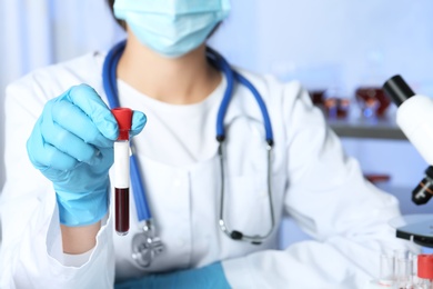 Photo of Laboratory worker holding test tube with blood sample for analysis, closeup