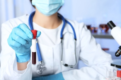 Laboratory worker holding test tube with blood sample for analysis, closeup