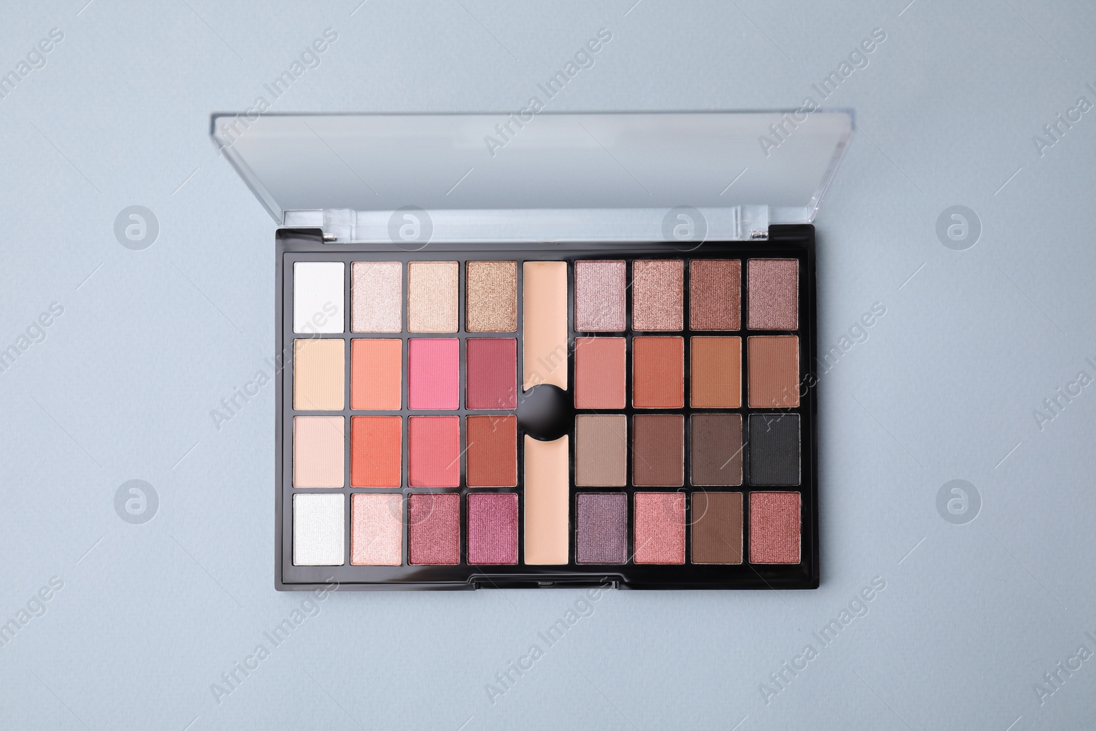 Photo of Beautiful eye shadow palette on light blue background, top view