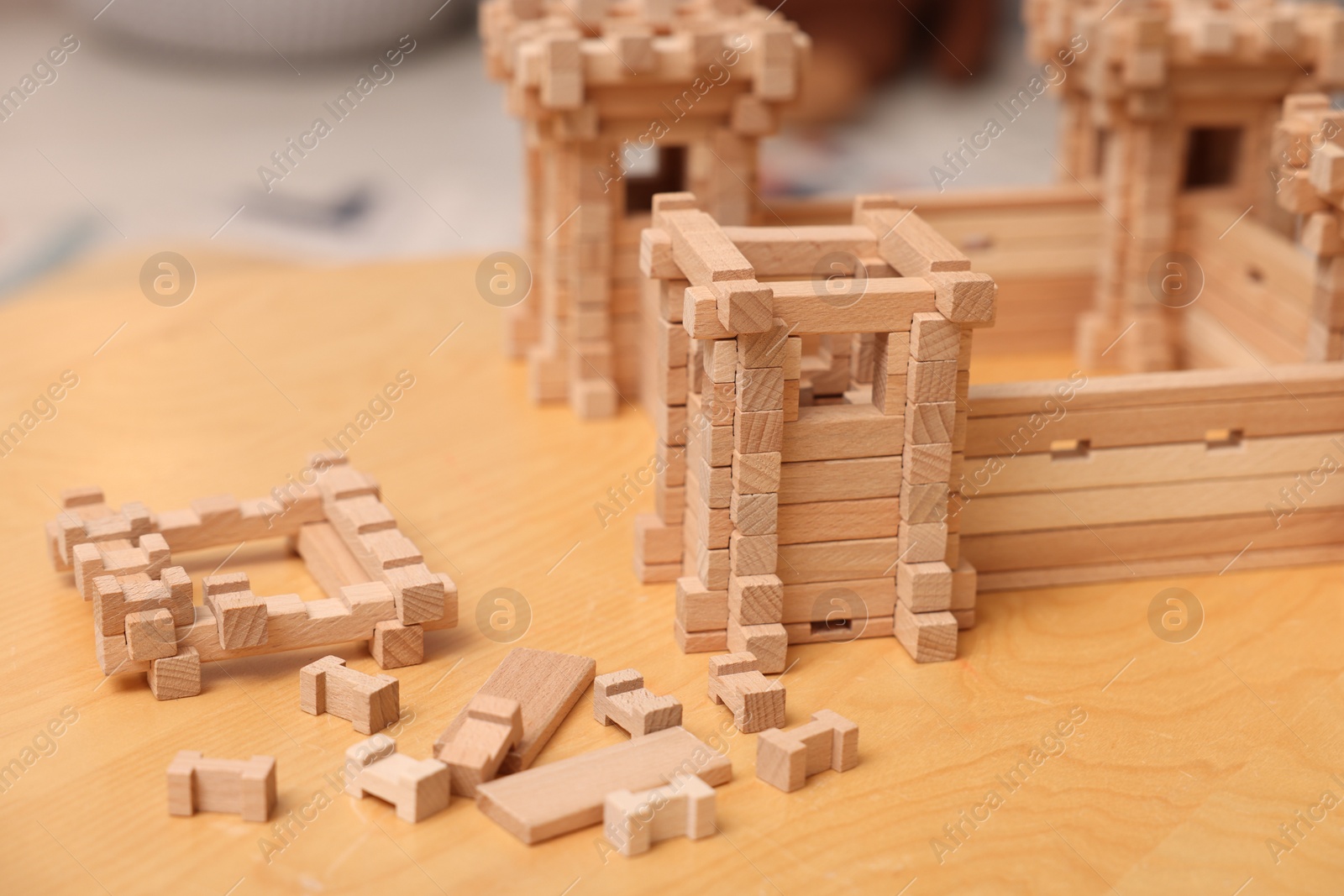 Photo of Wooden fortress and building blocks on table indoors. Children's toy