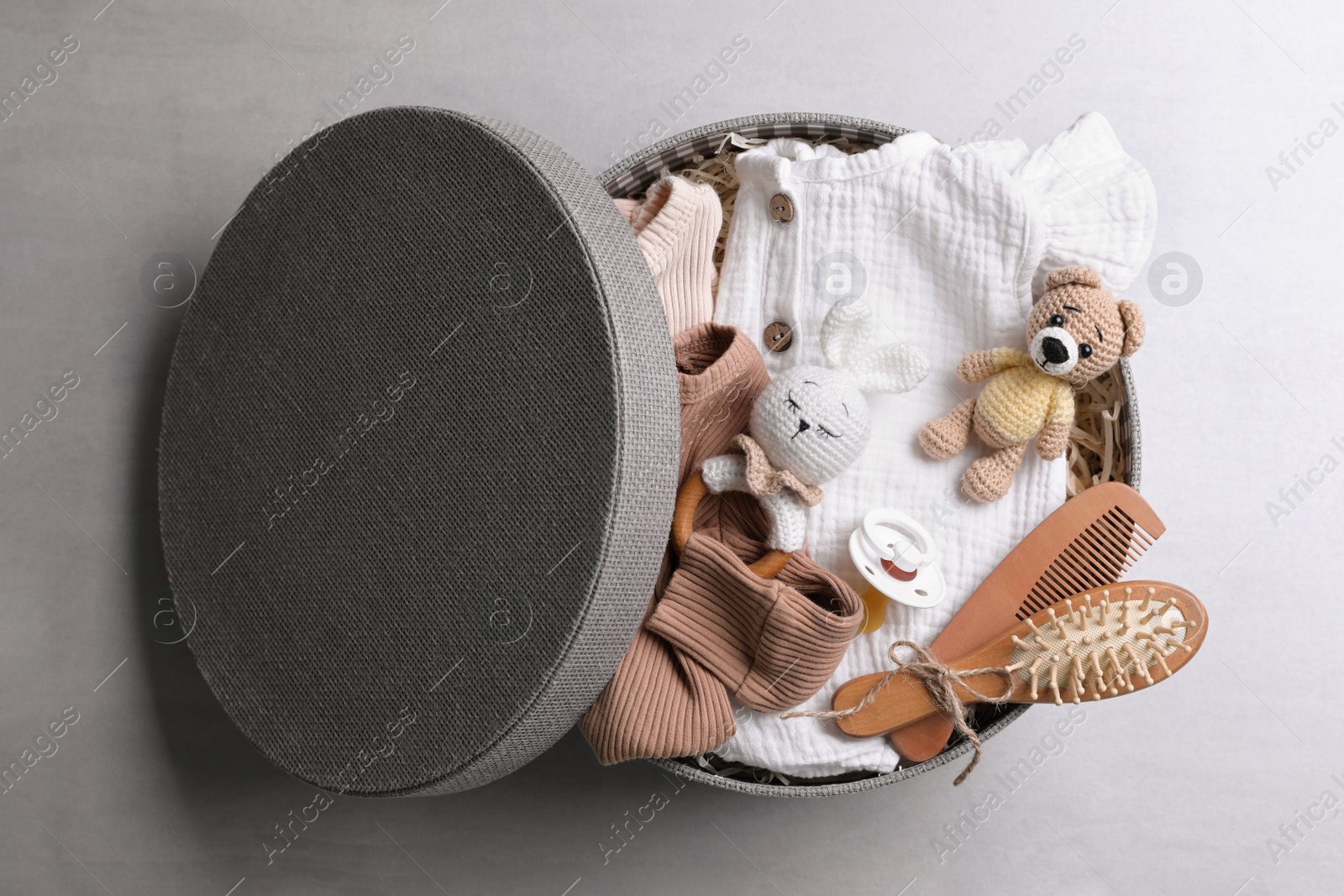 Photo of Box with baby clothes, toys and accessories on grey background, top view