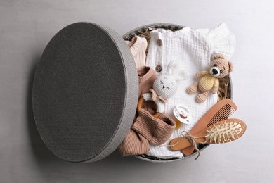 Photo of Box with baby clothes, toys and accessories on grey background, top view