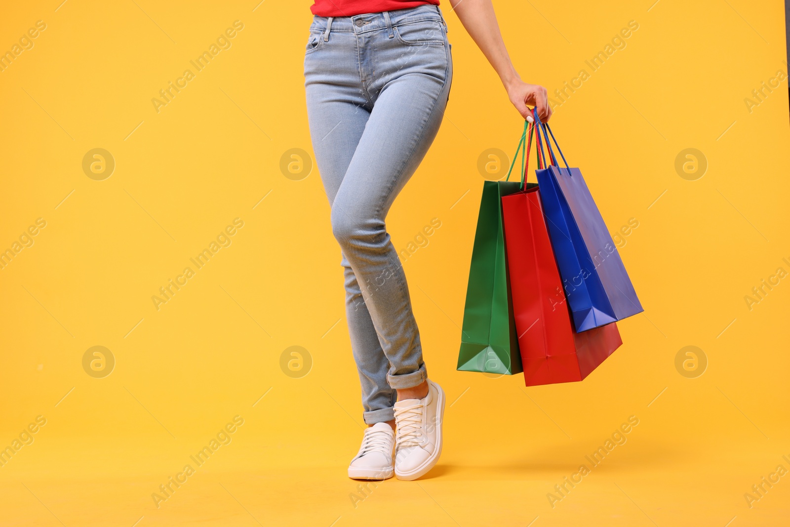 Photo of Woman with shopping bags on yellow background, closeup