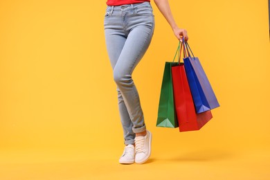 Photo of Woman with shopping bags on yellow background, closeup