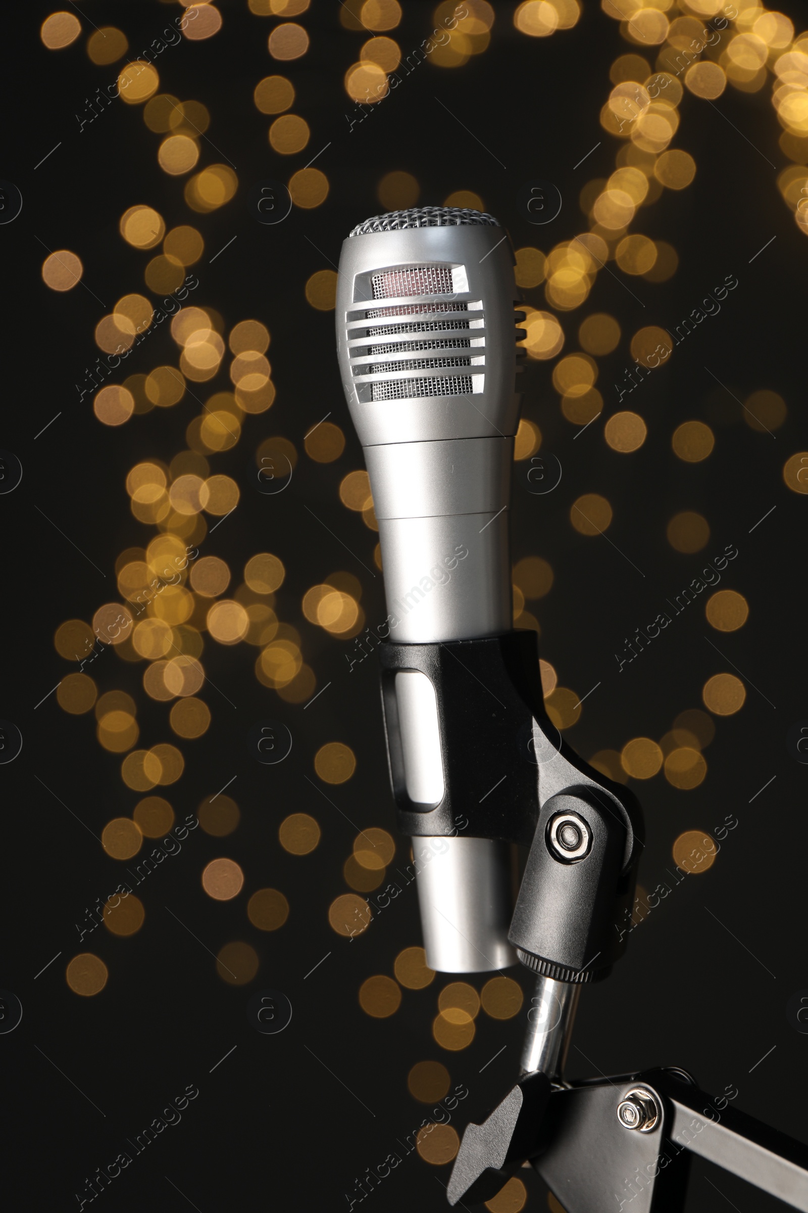 Photo of Stand with microphone against black background with blurred lights, closeup. Sound recording and reinforcement