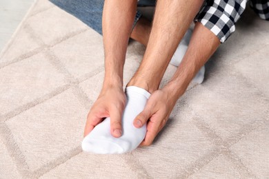 Photo of Man rubbing sore foot at home, closeup