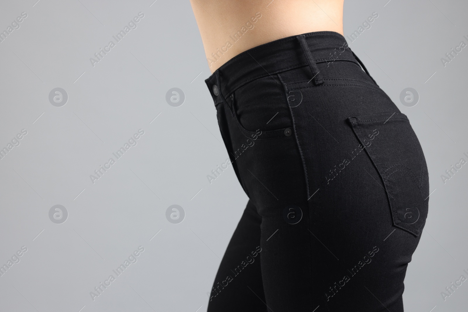 Photo of Woman wearing stylish black jeans on light gray background, closeup. Space for text