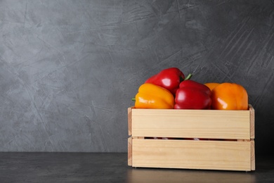 Photo of Wooden crate full of delicious fresh bell peppers on table, space for text