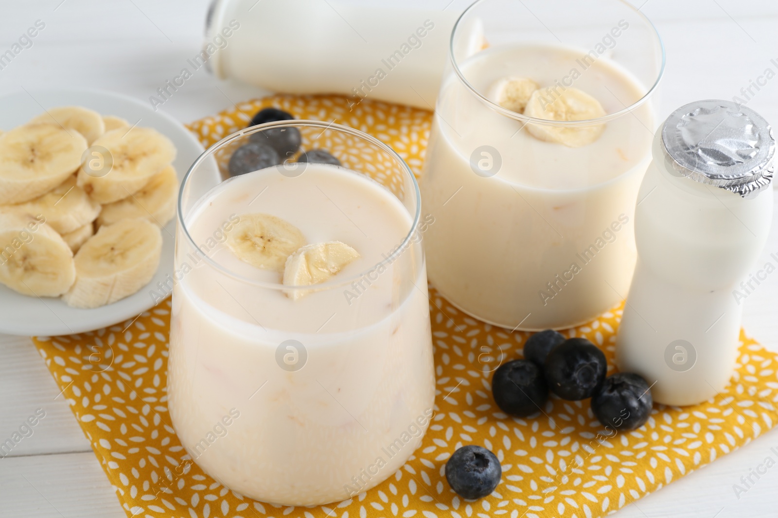 Photo of Tasty yogurt, banana and blueberries on white wooden table, closeup