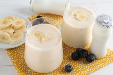 Tasty yogurt, banana and blueberries on white wooden table, closeup