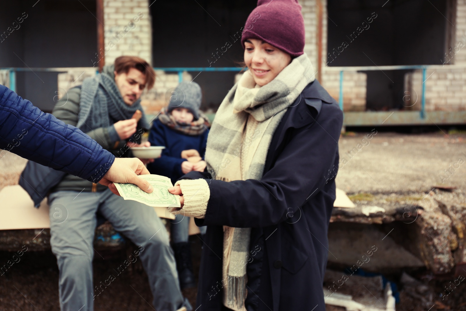 Photo of Poor young woman and her family begging for money on dirty street