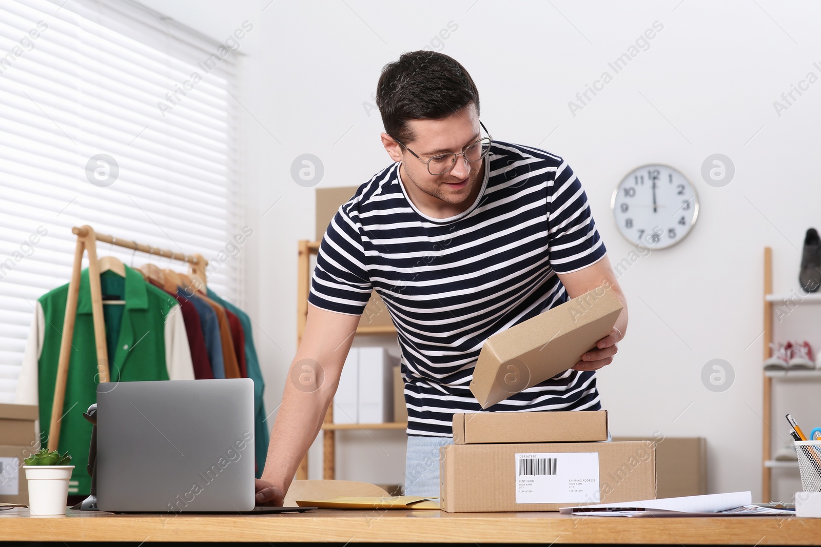 Photo of Seller with parcels and laptop working in office. Online store