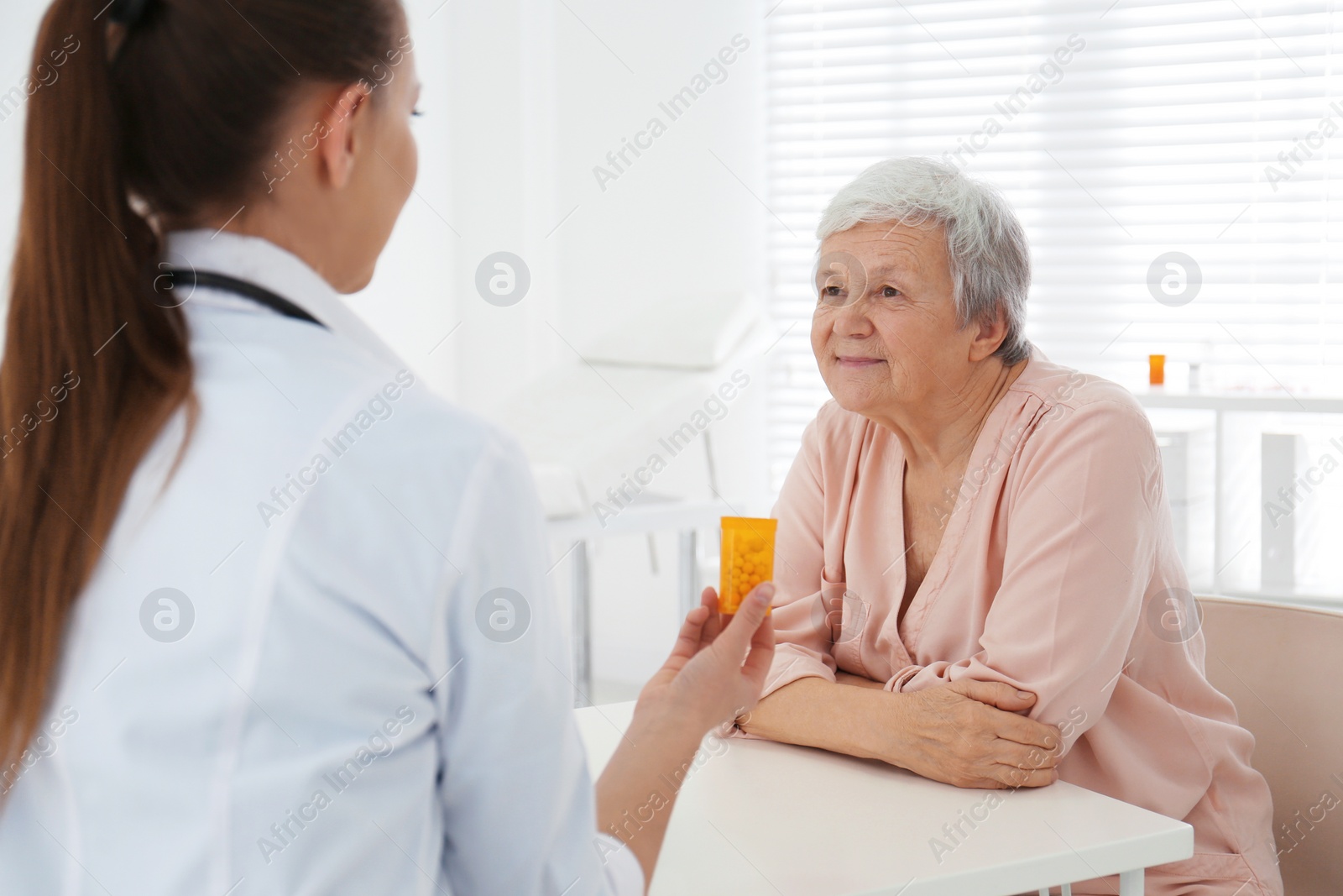 Photo of Doctor giving pills to senior patient in office