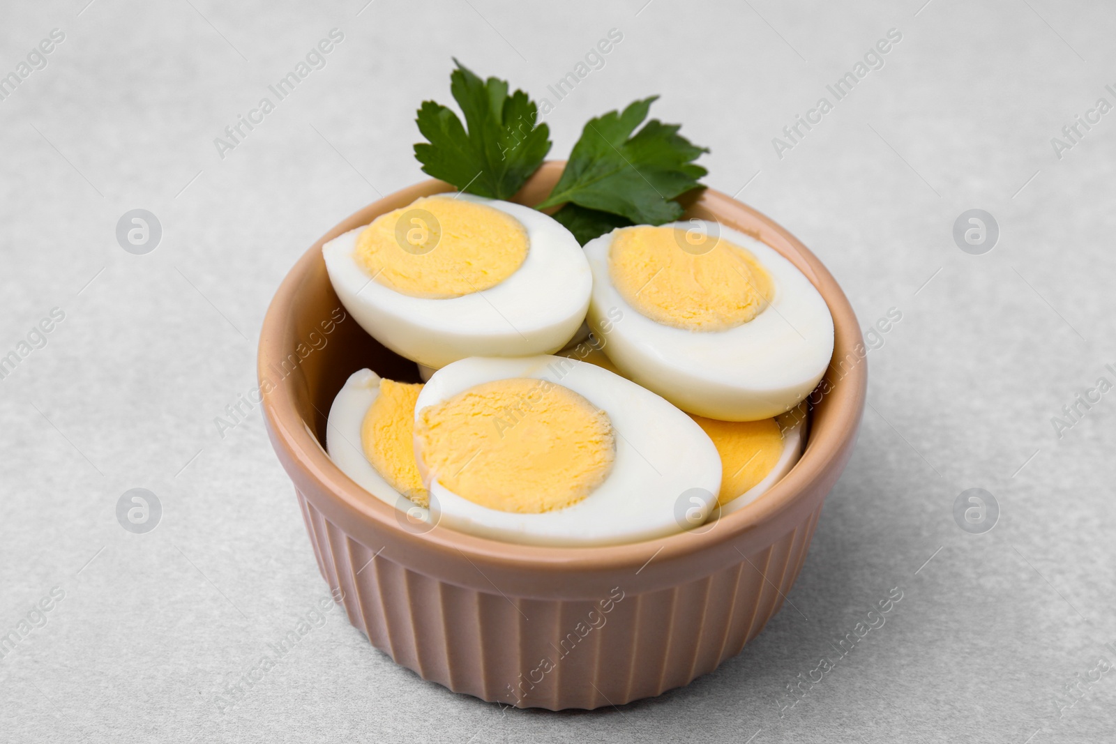 Photo of Fresh hard boiled eggs and parsley on light grey table