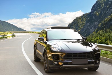 Image of Modern car on asphalt road in mountains