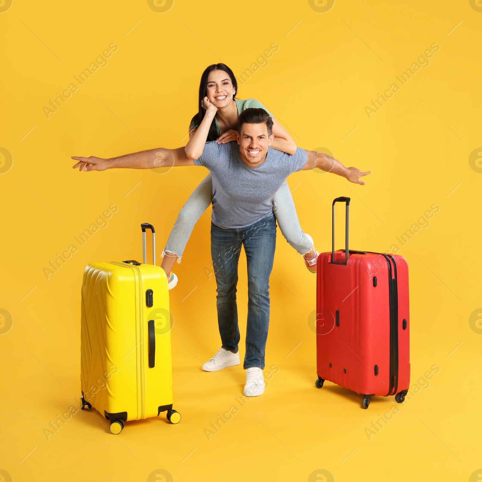 Photo of Happy couple with suitcases for summer trip on yellow background. Vacation travel