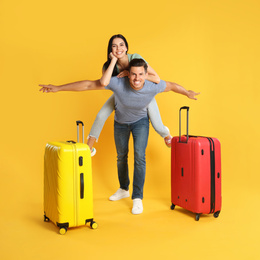 Happy couple with suitcases for summer trip on yellow background. Vacation travel